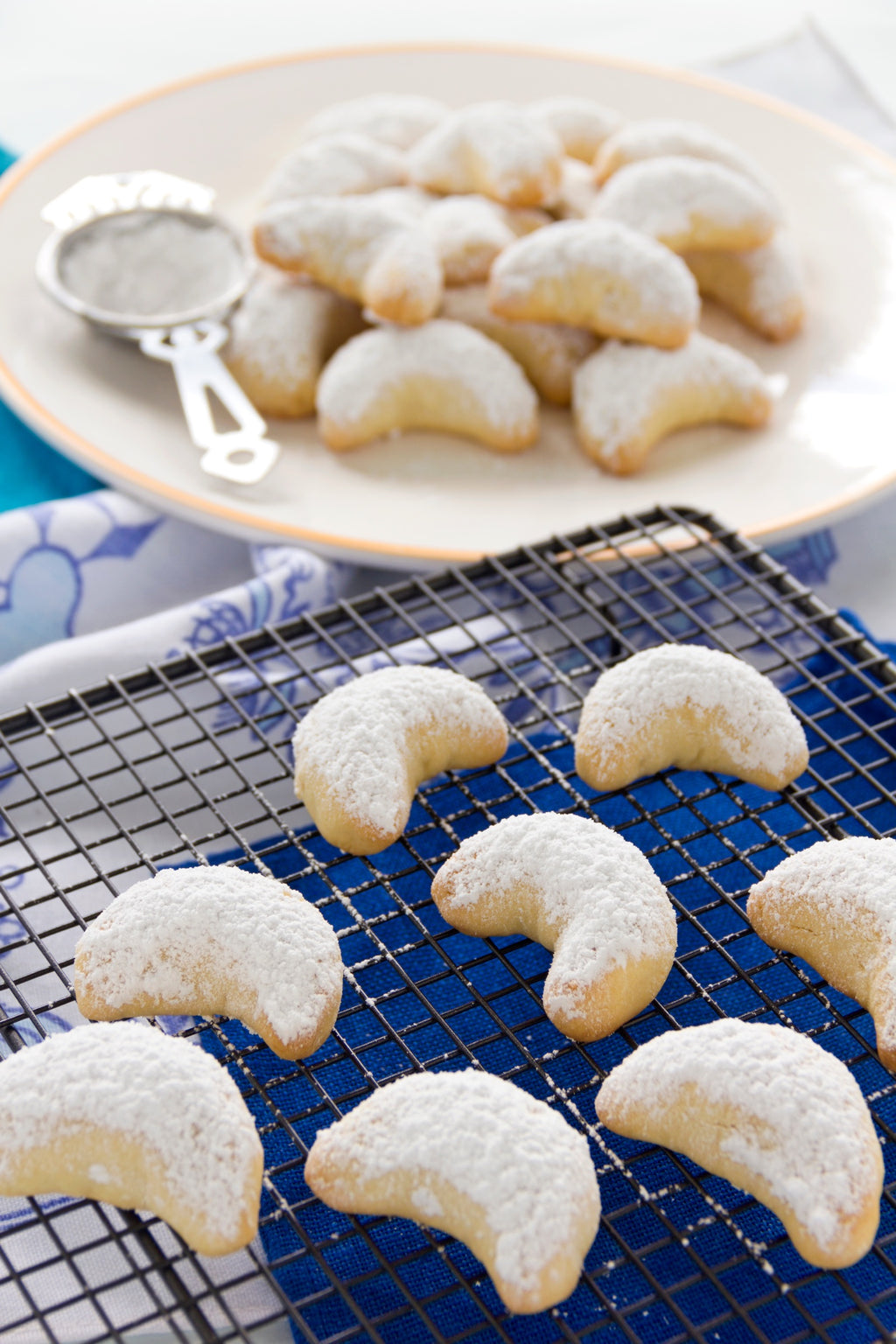 Freshly baked kourabiedes crescents dusted with icing sugar, cooling on a rack