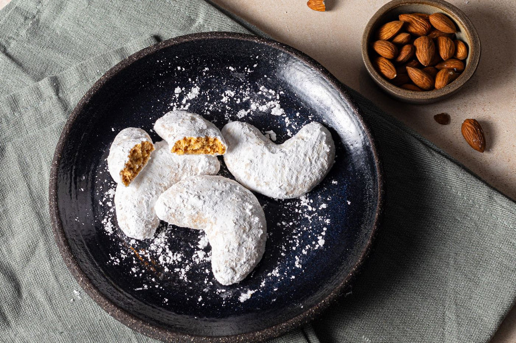 Zymi kourabiedes dusted with icing sugar, with almonds