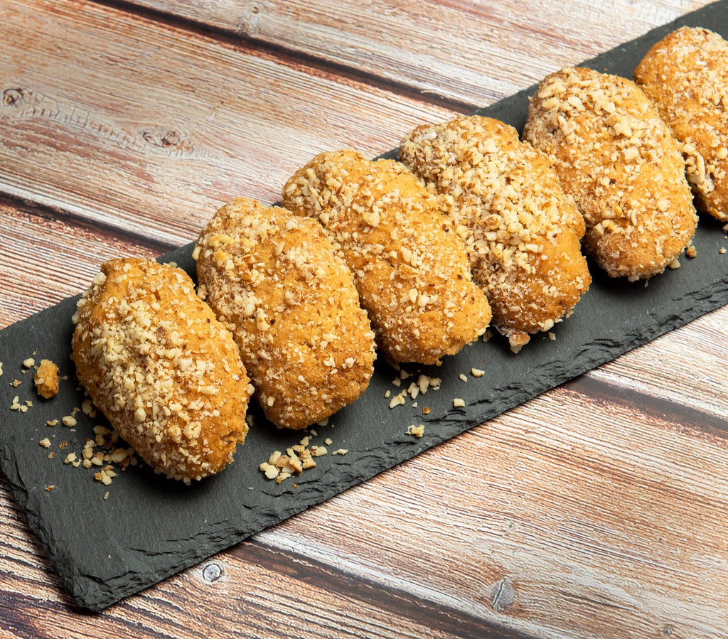 A row of walnut-topped melomakarona on a slate board