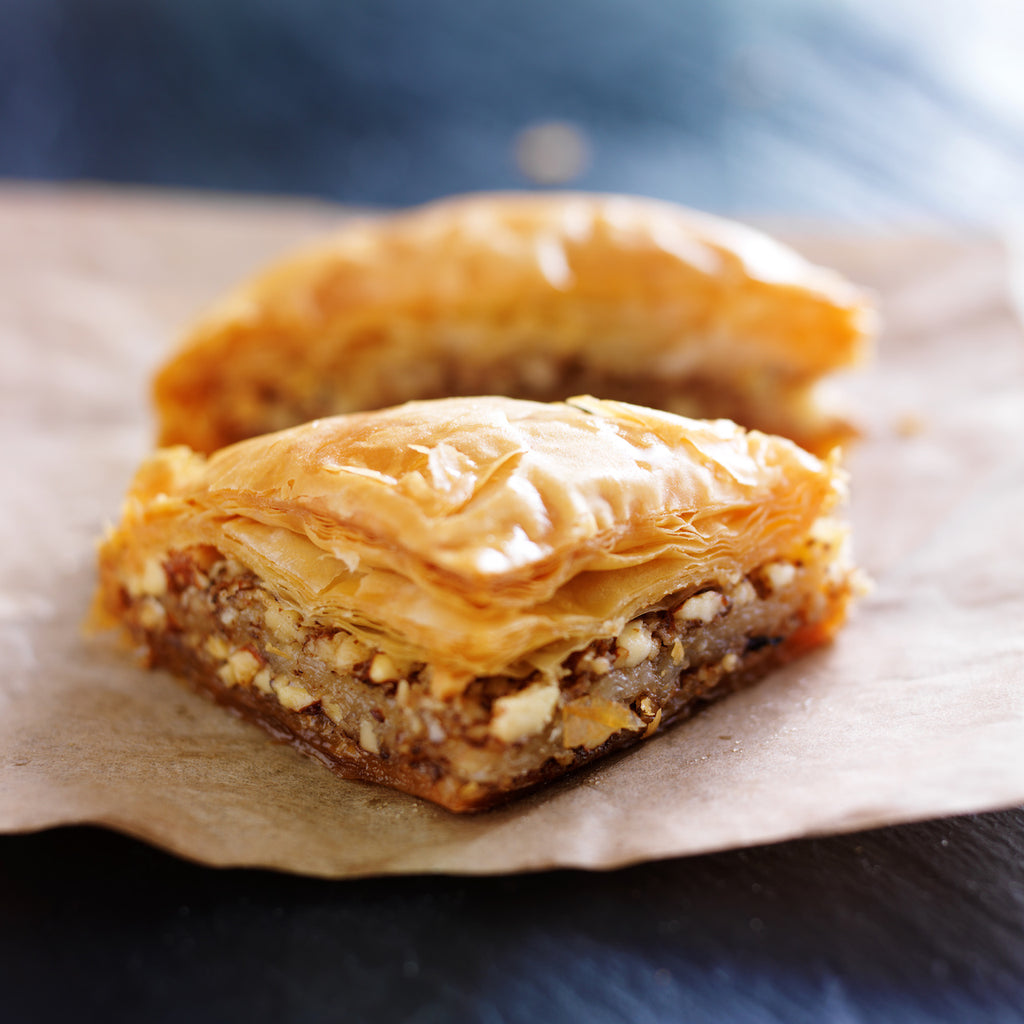 A slice of Greek baklava showing paper-thin flaky filo layers and cinnamon-walnut filling